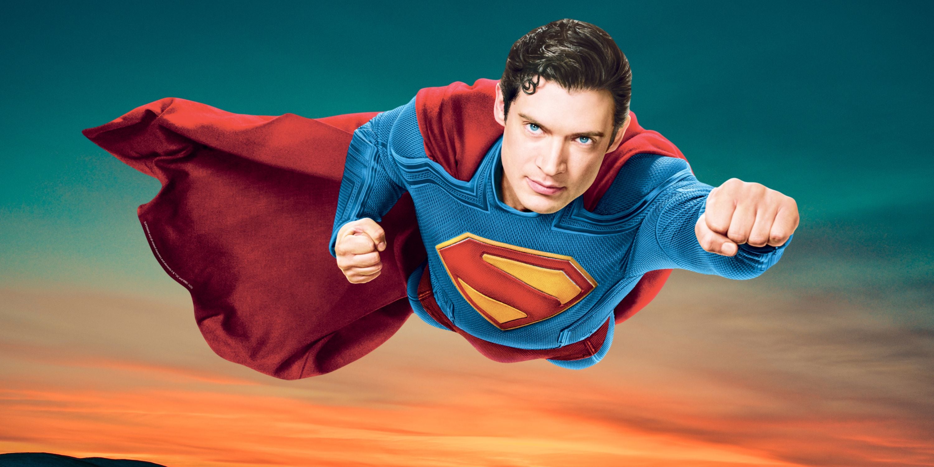 Superman flying with a red cape against a blue sky