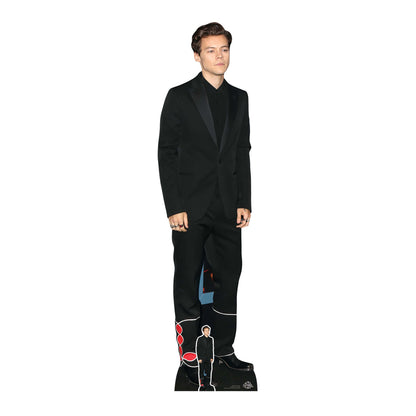 A cardboard cutout of Harry Styles in a black suit with a miniature figure of himself in the background.