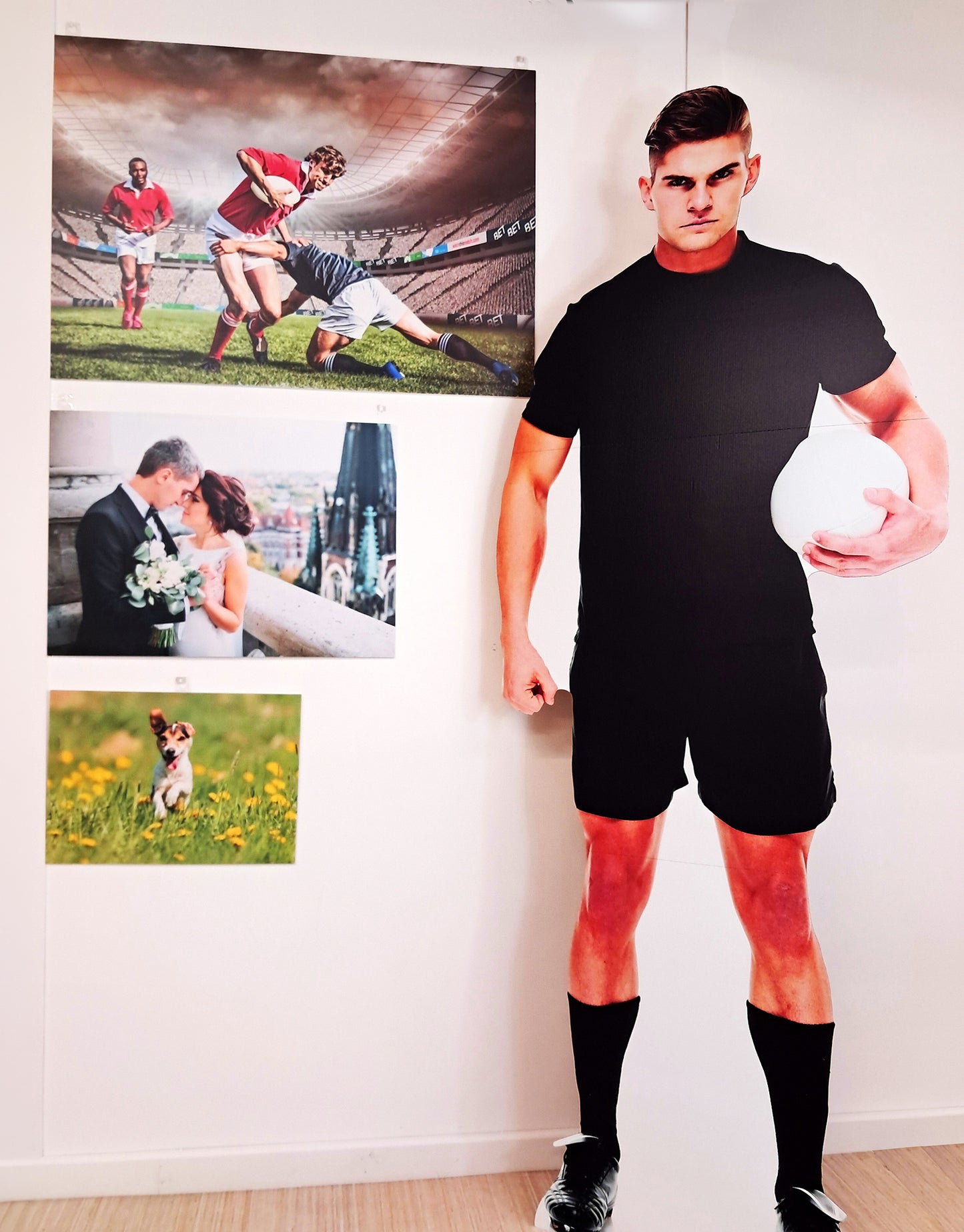 Man in sports gear holding a ball with wedding and personalised prints on the wall.
