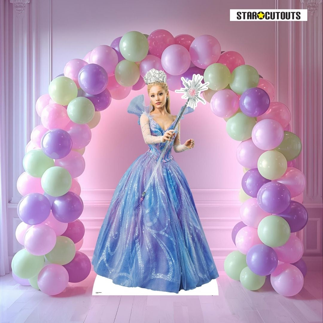 Cardboard cutout of a Glinda Wicked for Good Cardboard Cutout in a blue dress with a balloon arch and 'Star Cutouts' branding.